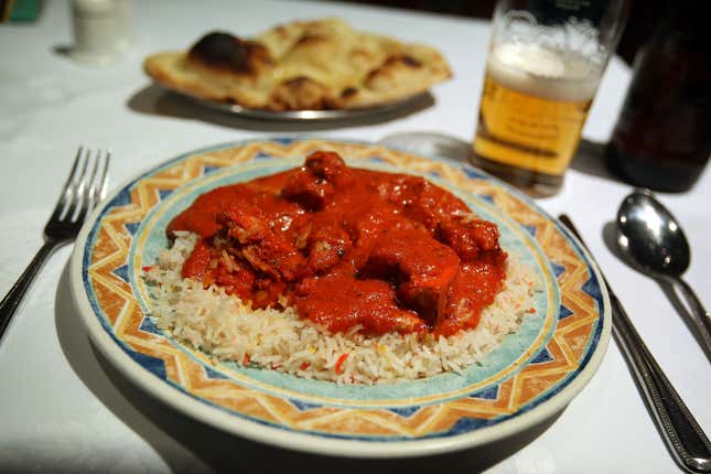 Chicken tikka masala sits on a bed of rice atop a plate with a sunburst-like design